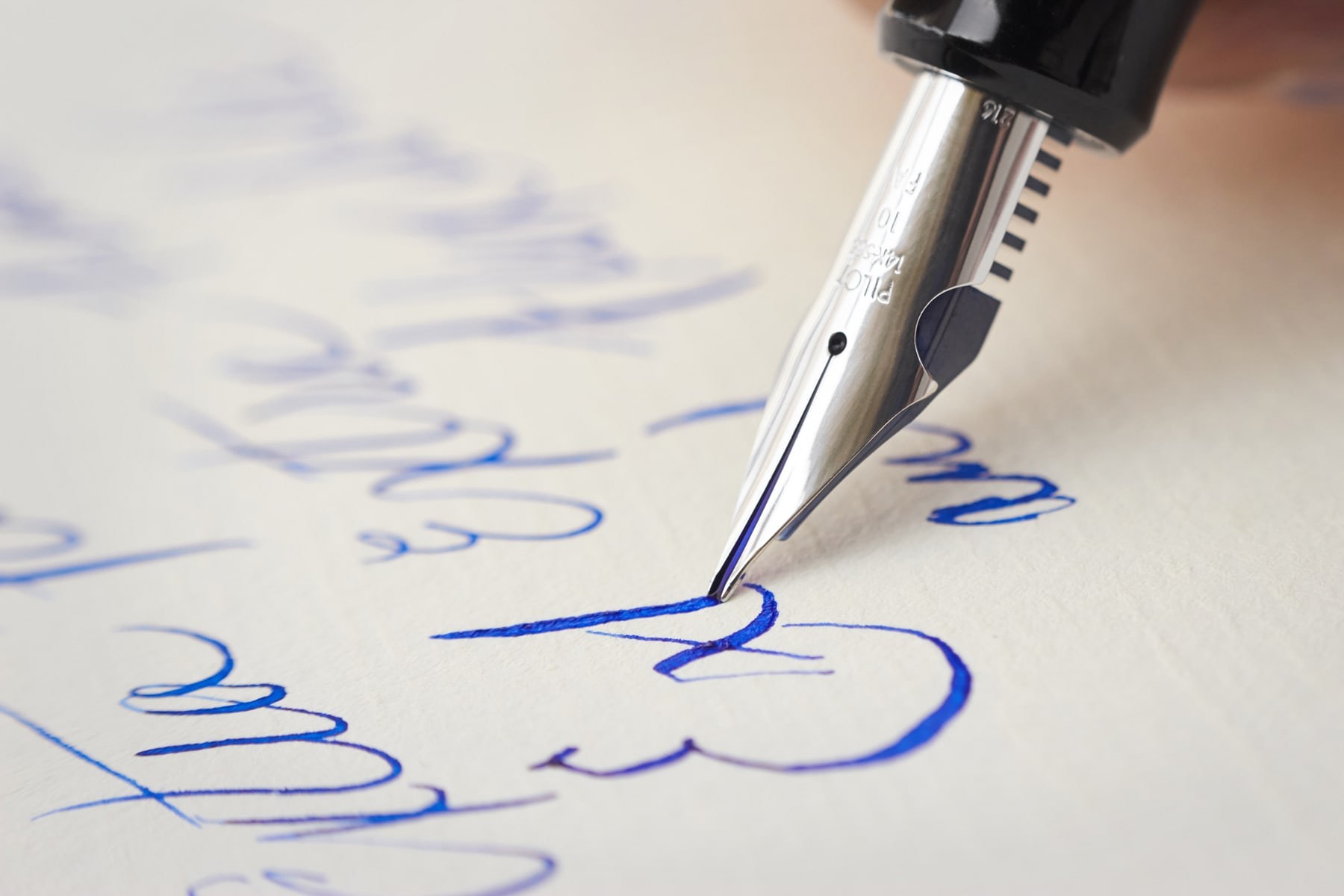 A fountain pen writing in cursive on paper